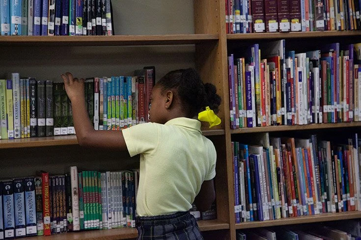 A student selects a book from the shelves
