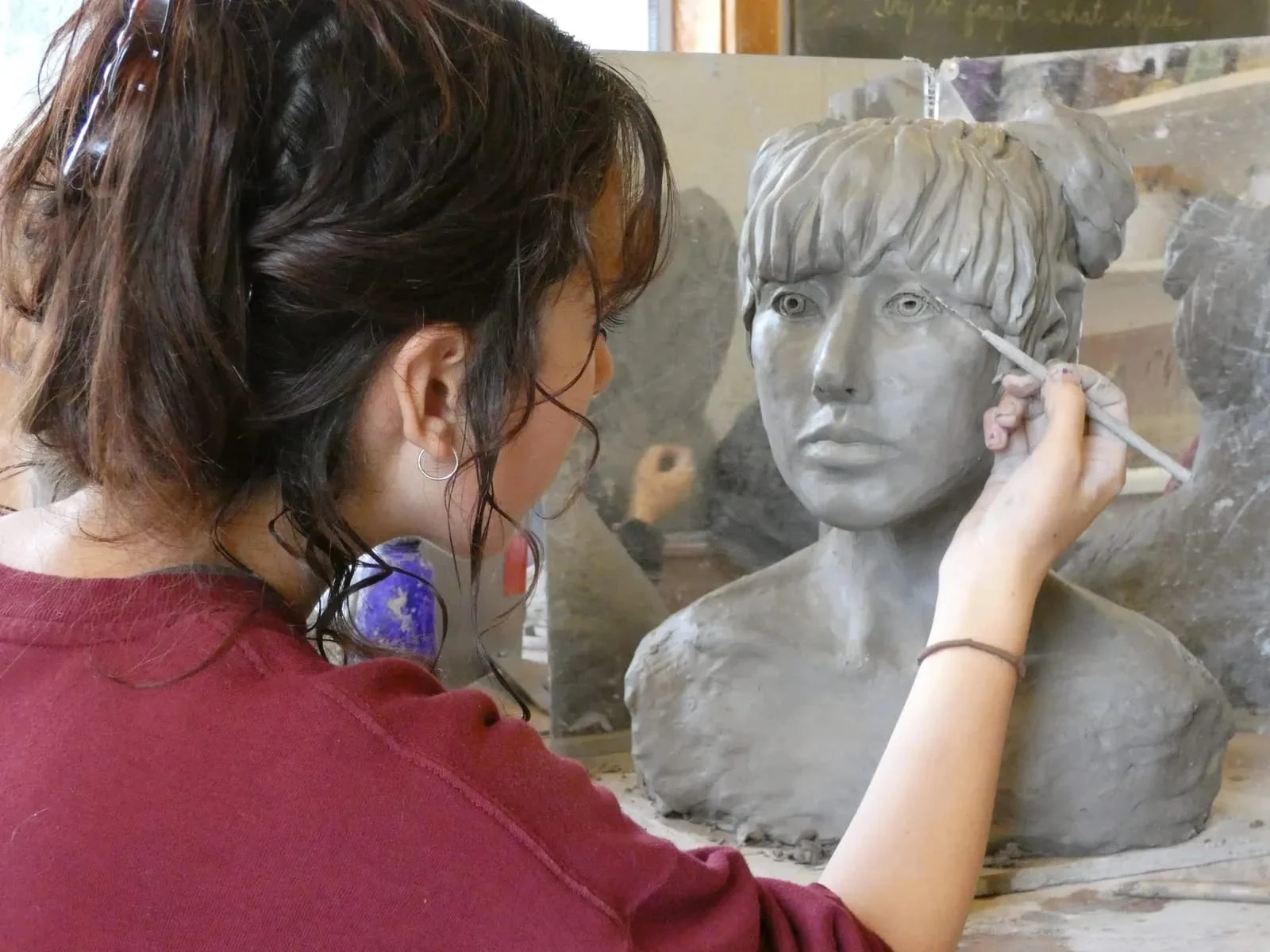 A student models a clay portrait