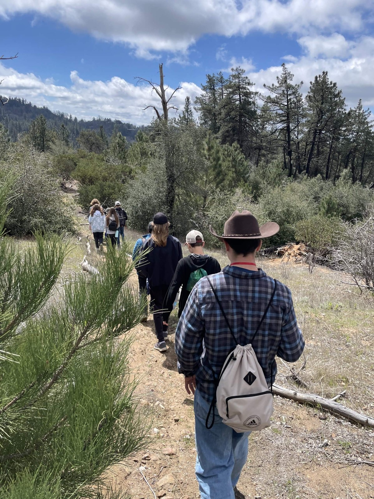 Official outdoor-education photo: a group hike on a wooded trail