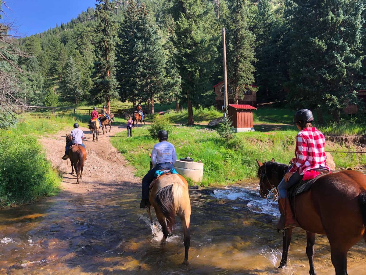 Cheley Family Camp: a horseback-riding group crossing a shallow stream.