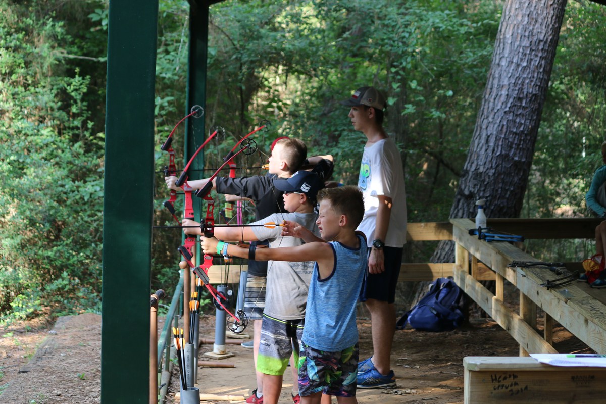 Campers practise aiming bows at the archery range