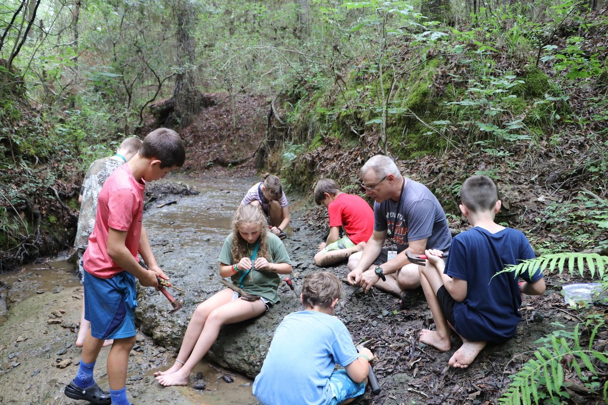 A small group takes part in an outdoor-skills activity in the woods