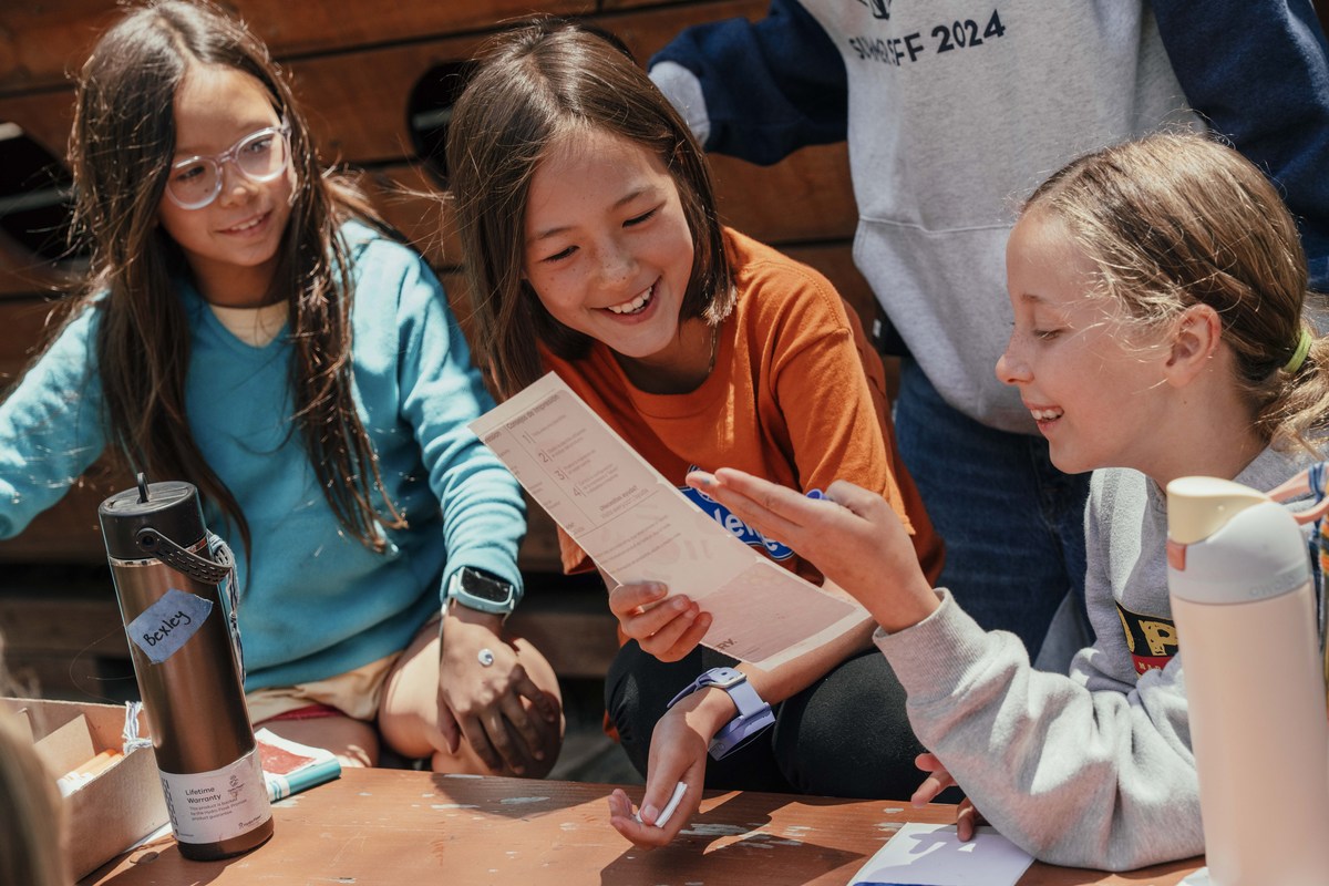 Campers talk and work together around a table