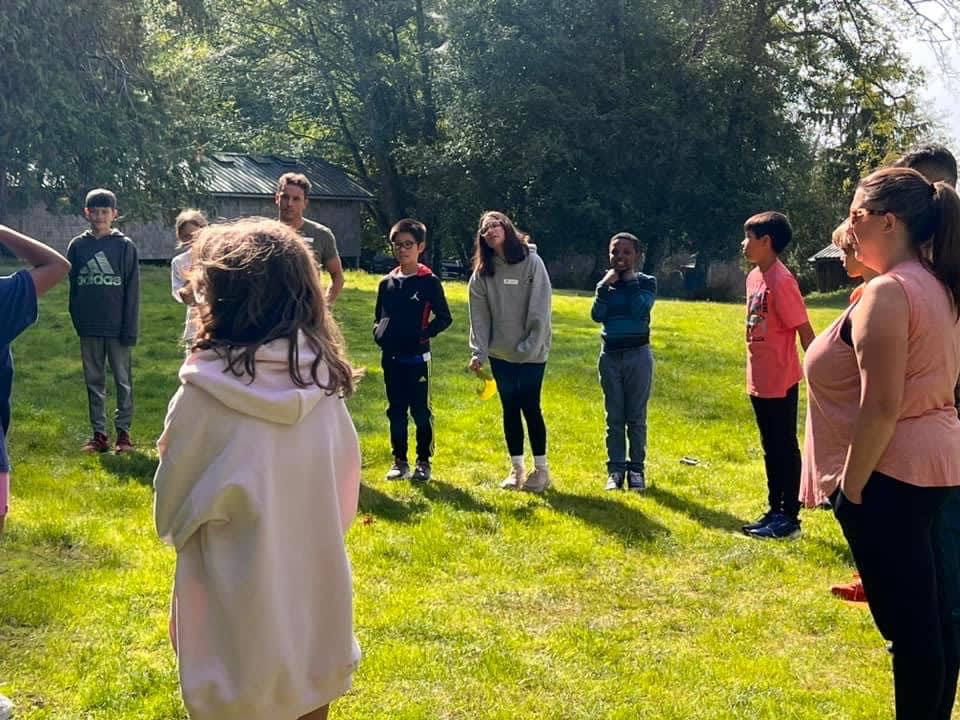 2023 school-trip archive: students gather in a circle on the lawn at Camp Orkila.