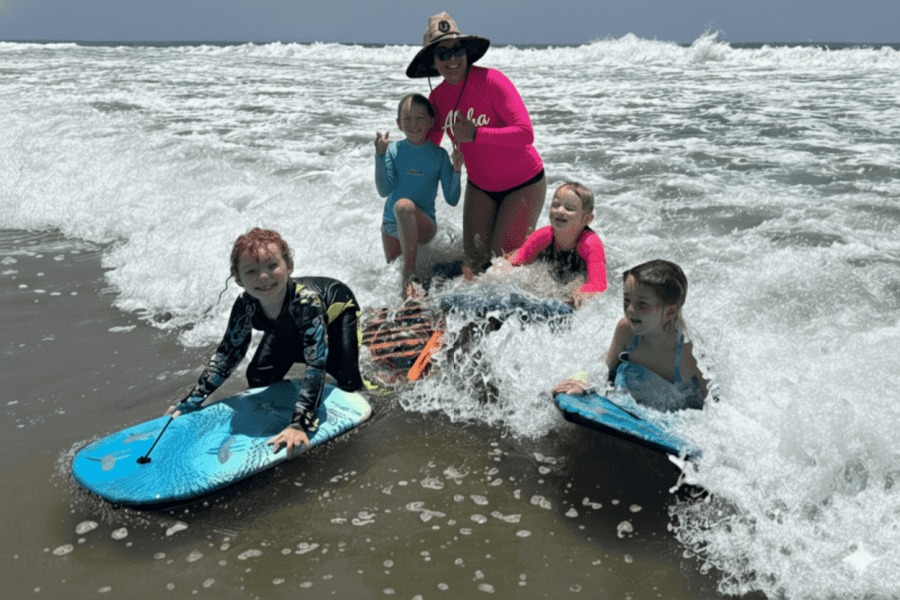 Staff accompany campers with boogie boards near the shoreline