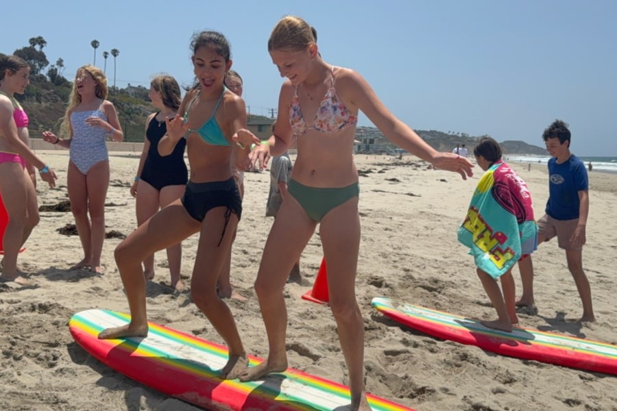 Campers practise a surfing stance on the beach