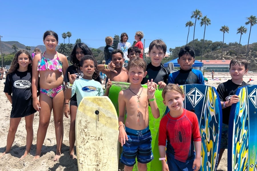 Campers gather on the beach with boogie boards