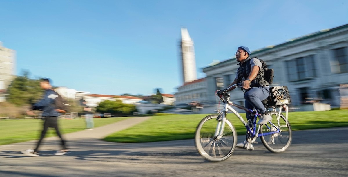 A cyclist passing the campus lawn and Campanile