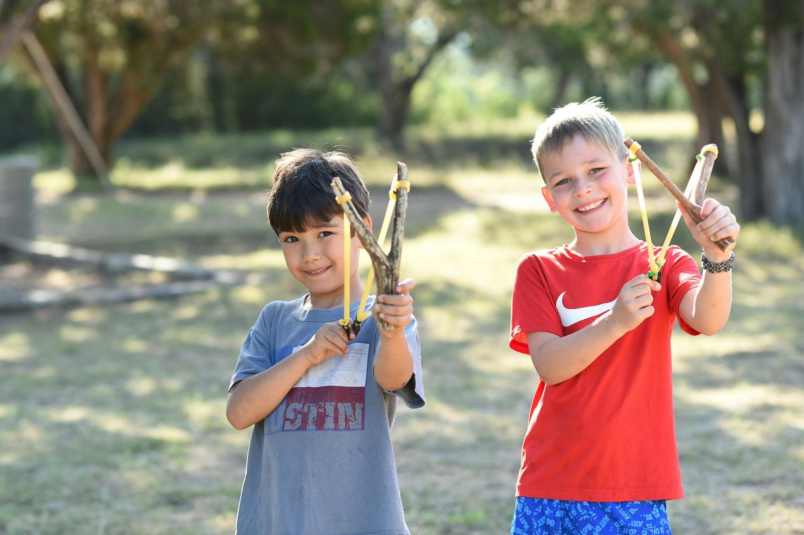 Two campers hold slingshots outdoors