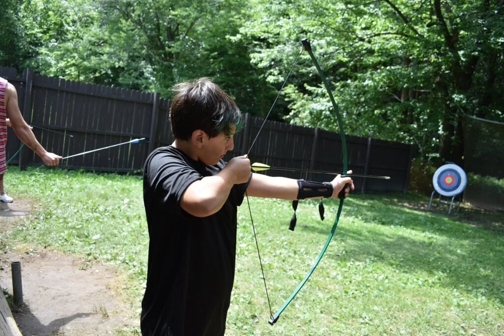营员在户外射箭场拉弓瞄准