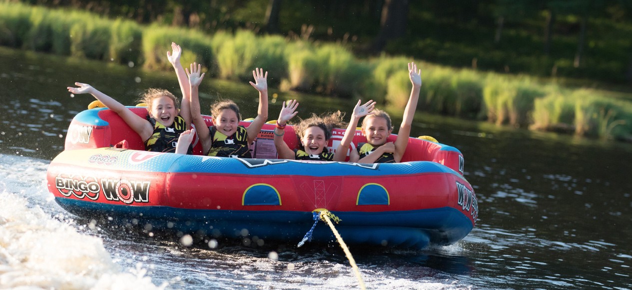 Campers sharing a towable tube on the lake