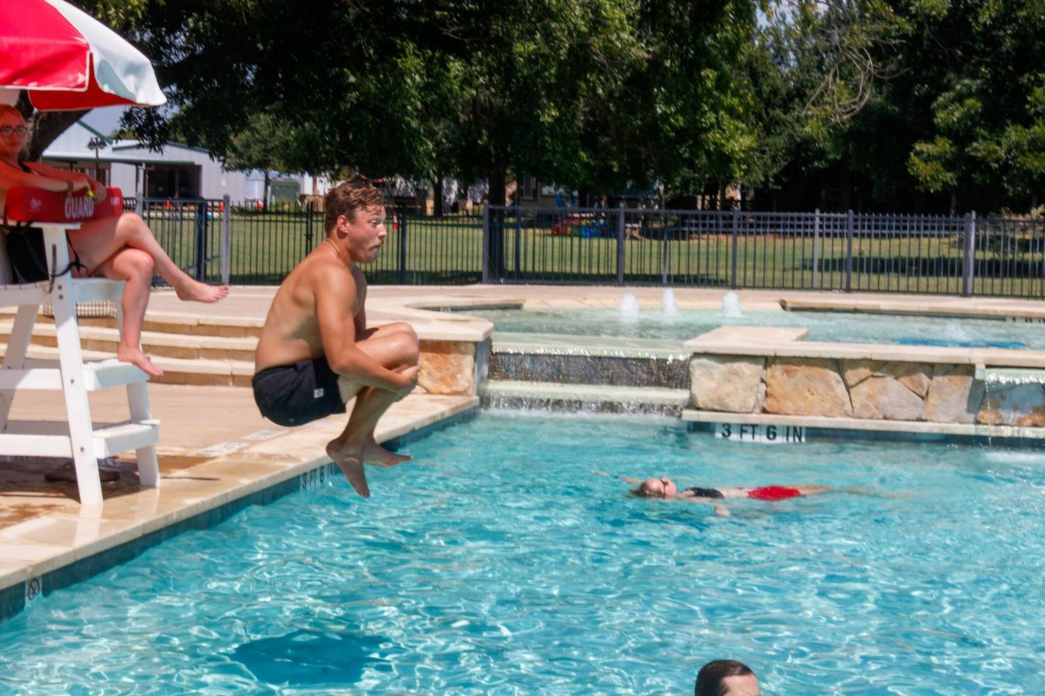 A camper jumps from the poolside into the water