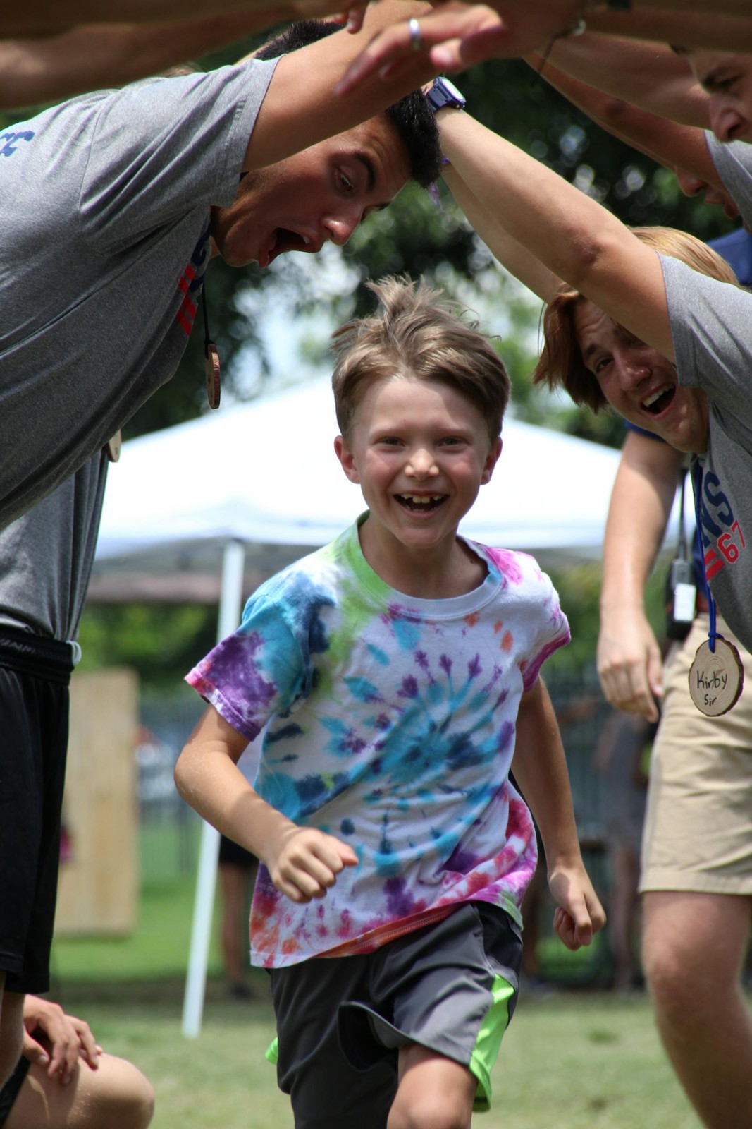 A camper runs beneath an arch of raised arms