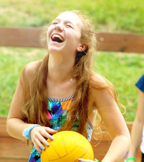 A camper laughing during a ball activity