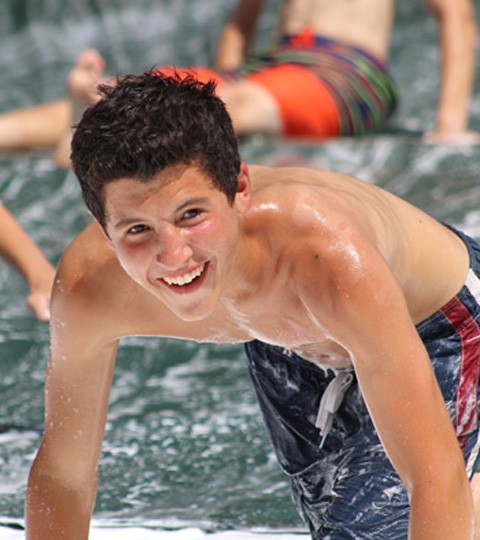 A camper enjoying a water-slide activity