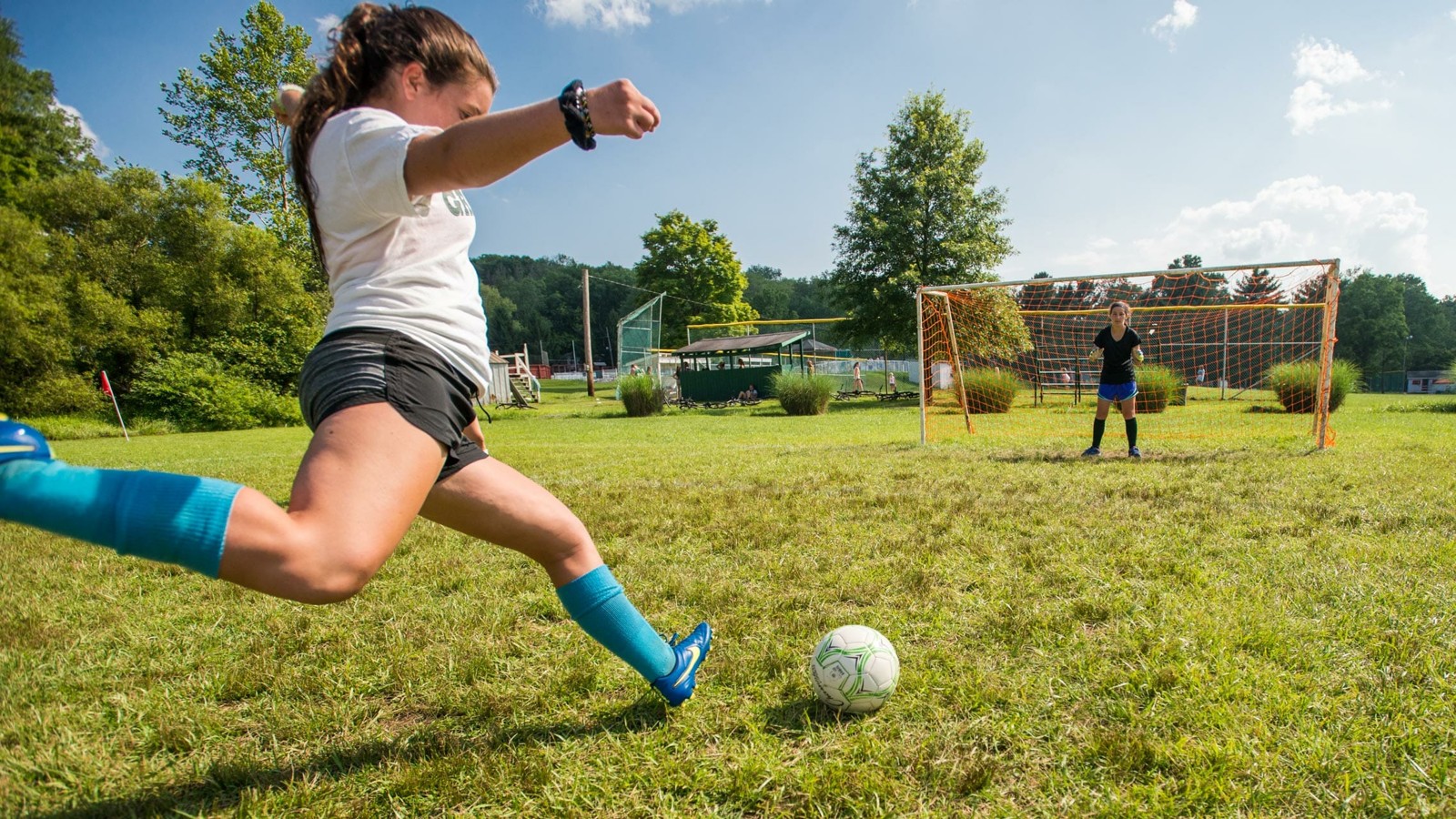 A camper practicing a soccer kick