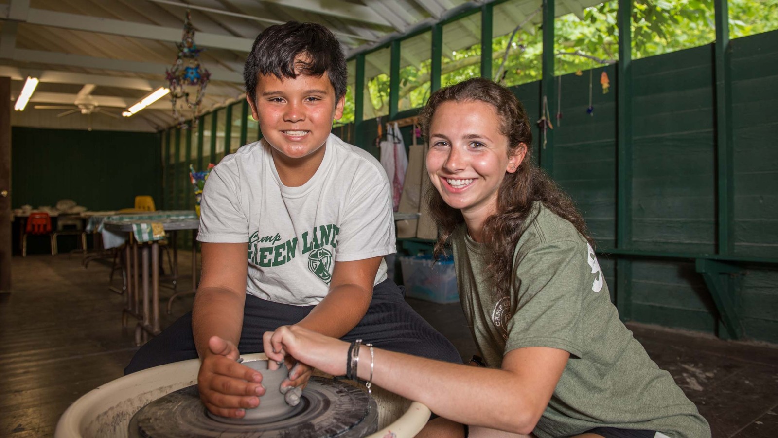 A camper learning pottery on a wheel