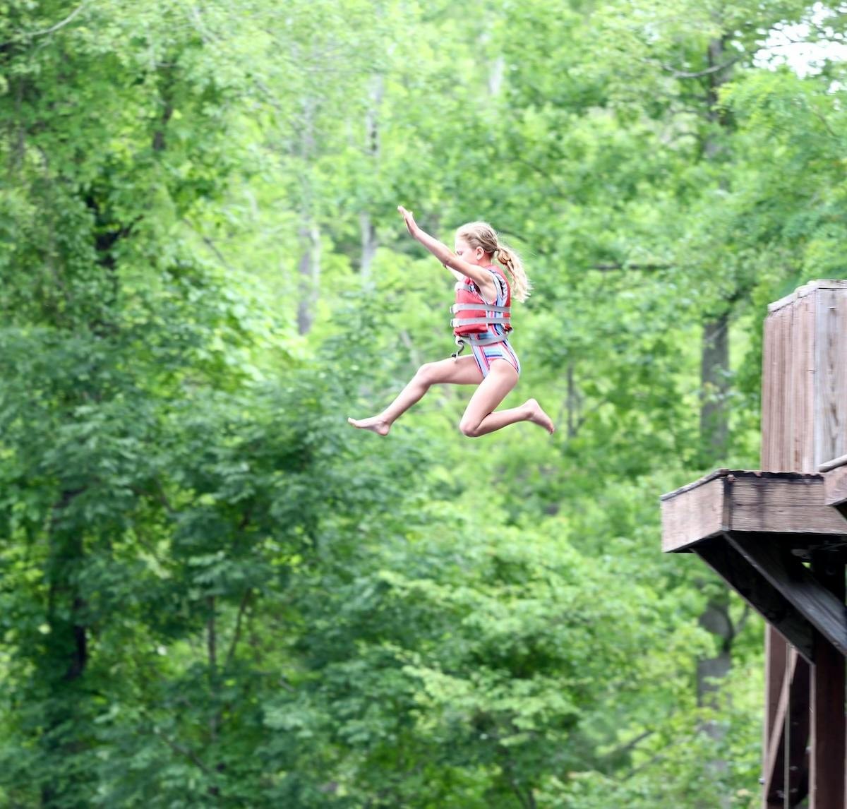 A camper jumps from a wooden platform
