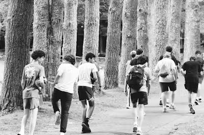 Campers walk together along a wooded path, in a black-and-white photograph