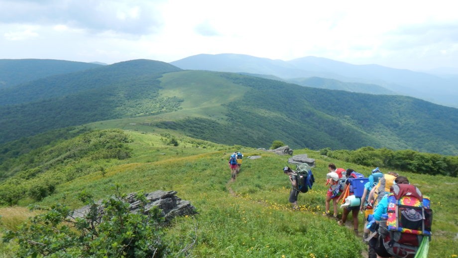 A hiking group walks along a grassy mountain ridge