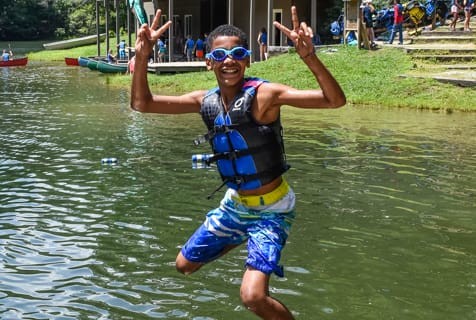 A camper wearing a life jacket jumps into the water