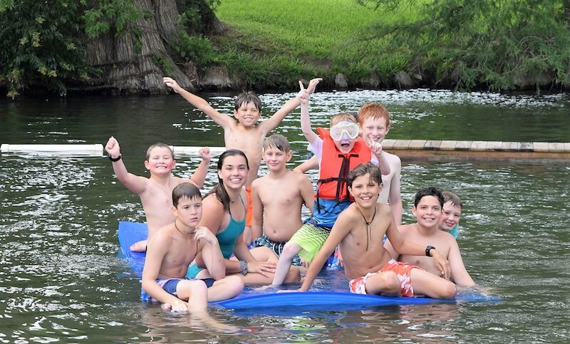Campers gather on a floating mat in the water