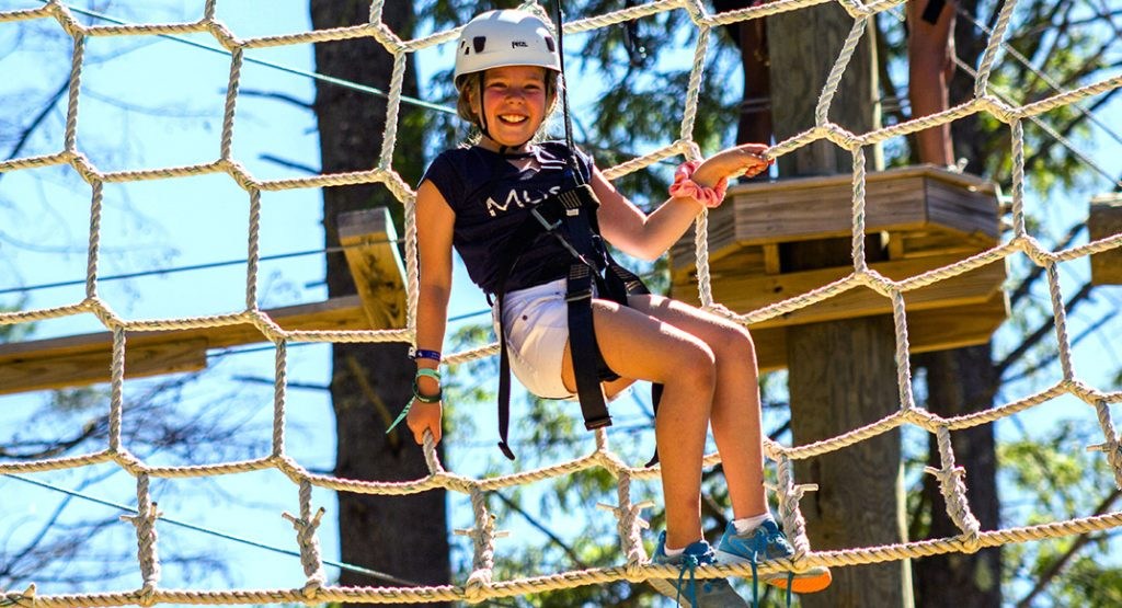 A camper on a climbing-net challenge