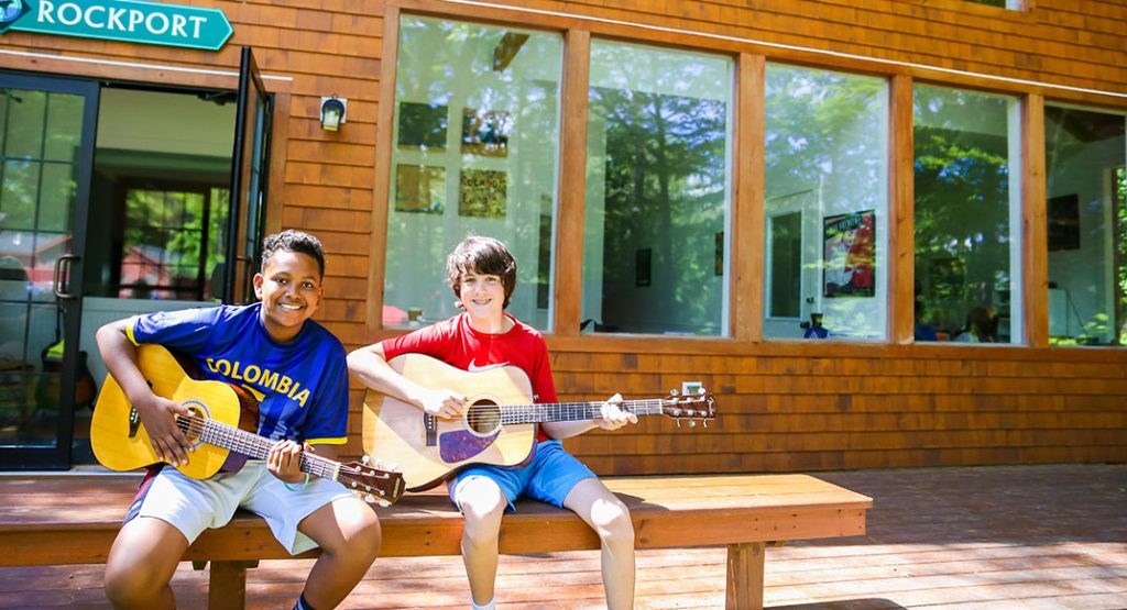 Playing guitars outside a camp building