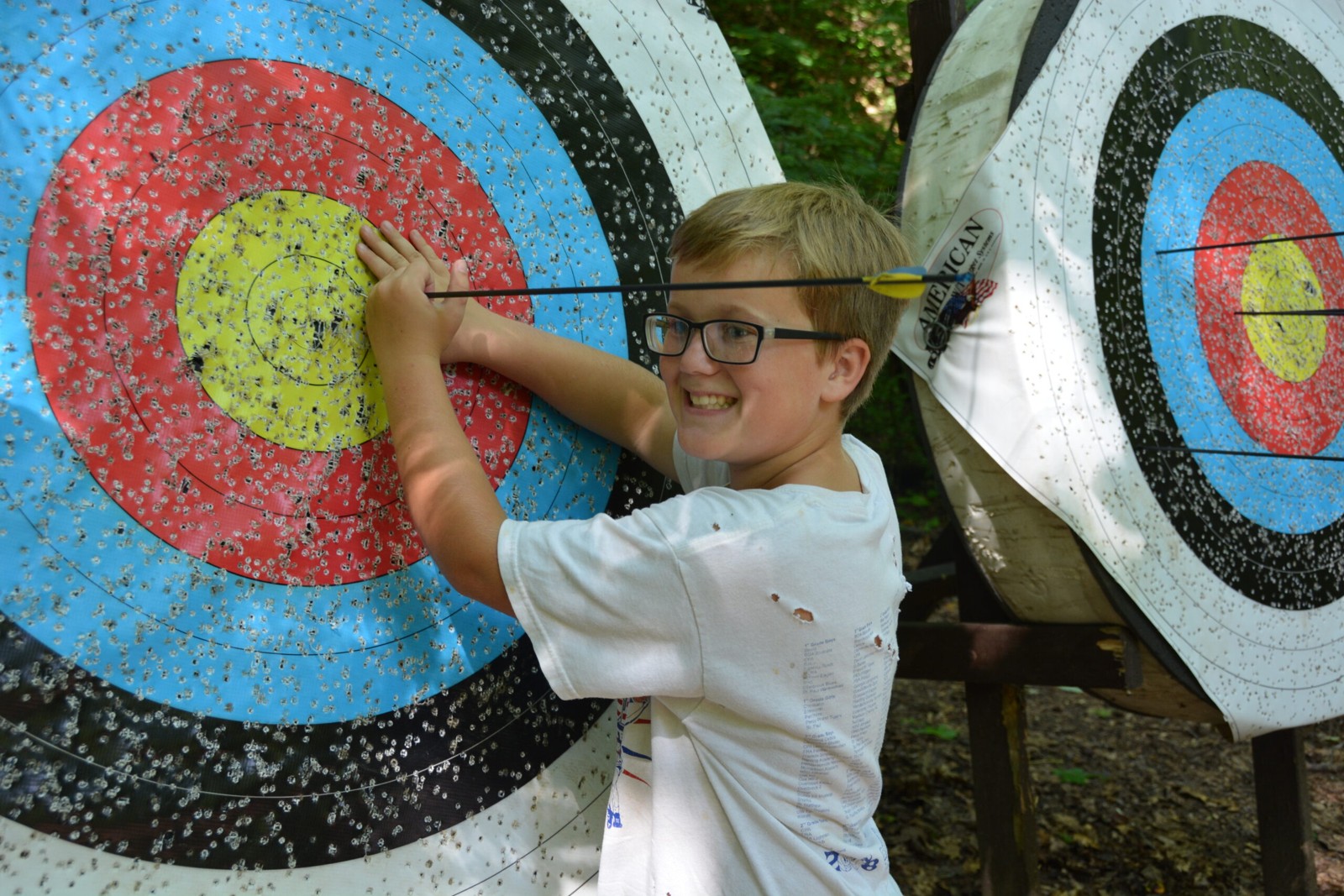A camper poses beside a target at the archery range