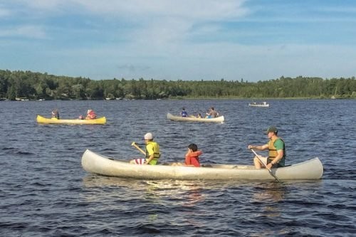 Campers paddle canoes on the lake