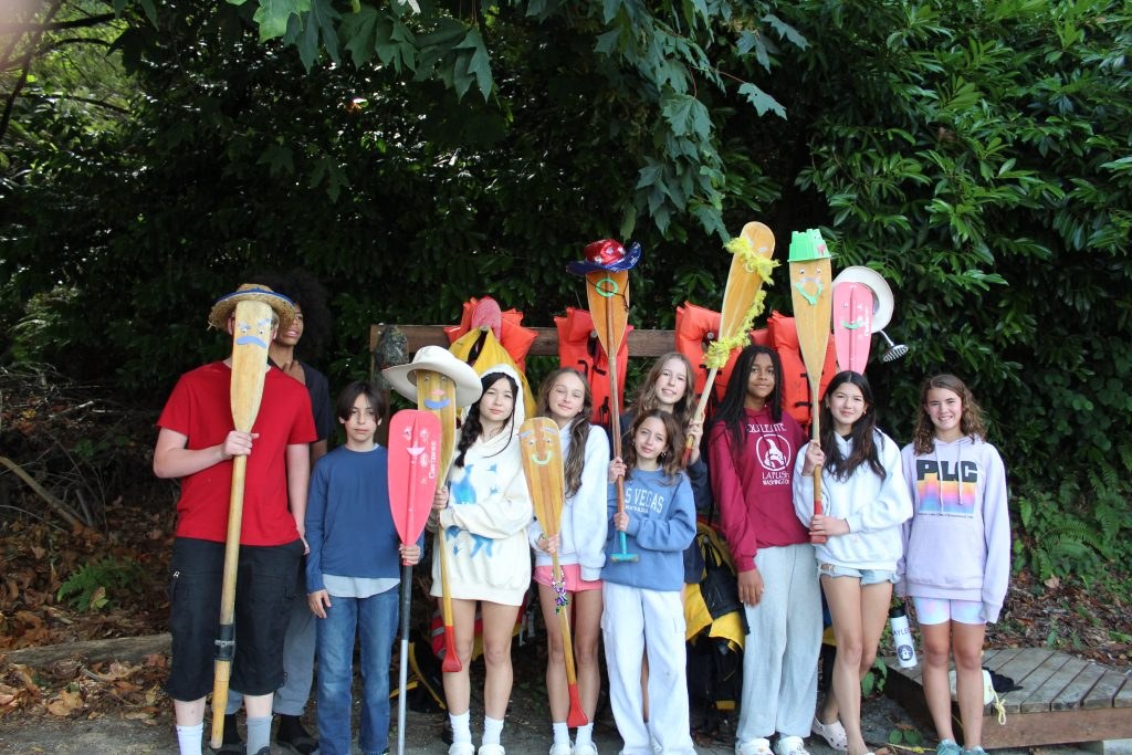 Campers holding paddles beside the woodland