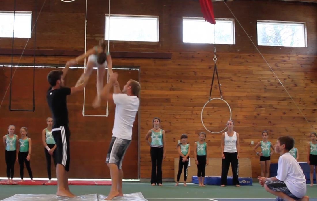Staff assisting a camper with an aerial skill