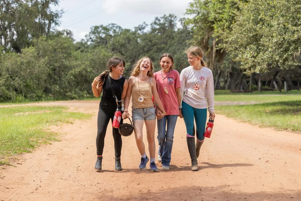 Campers walk together along a tree-lined camp path