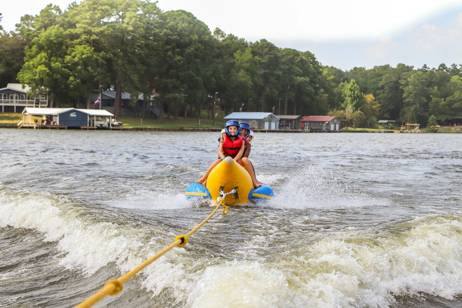 Campers ride a towed inflatable boat across the lake