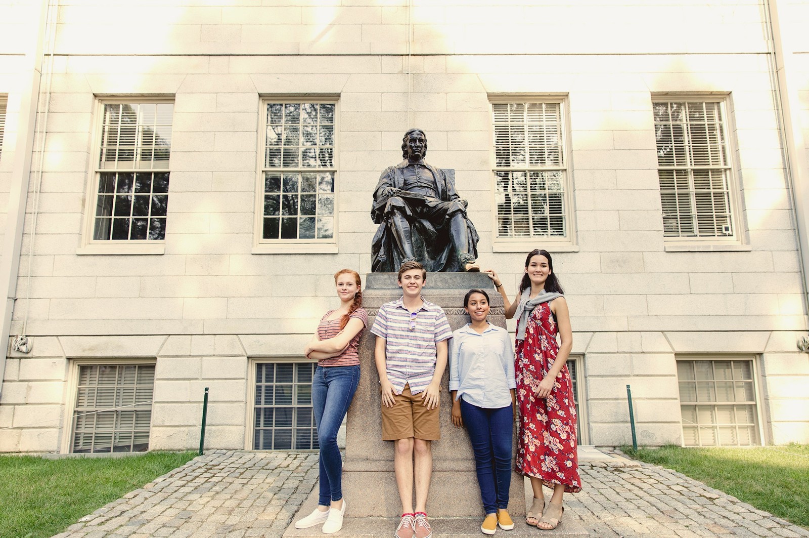Students beside the John Harvard statue in Harvard Yard