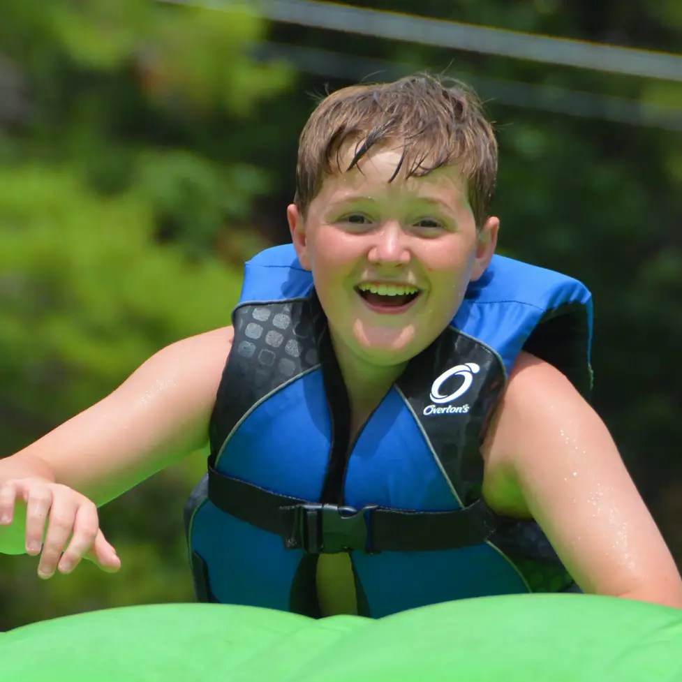 A camper wearing a life jacket by the lake