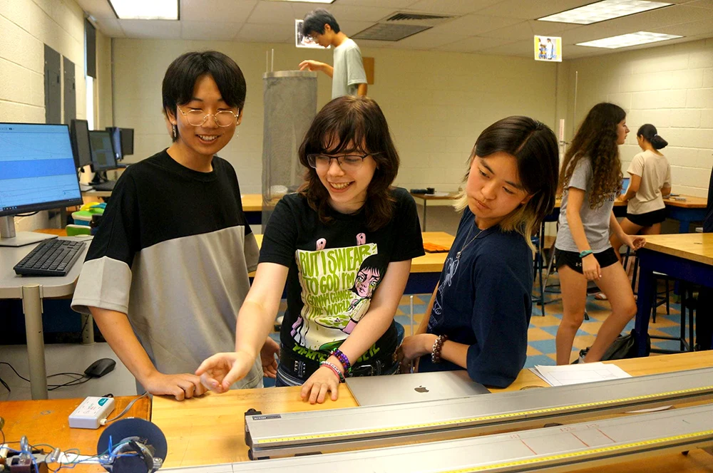 Students work together around apparatus on a physics lab bench