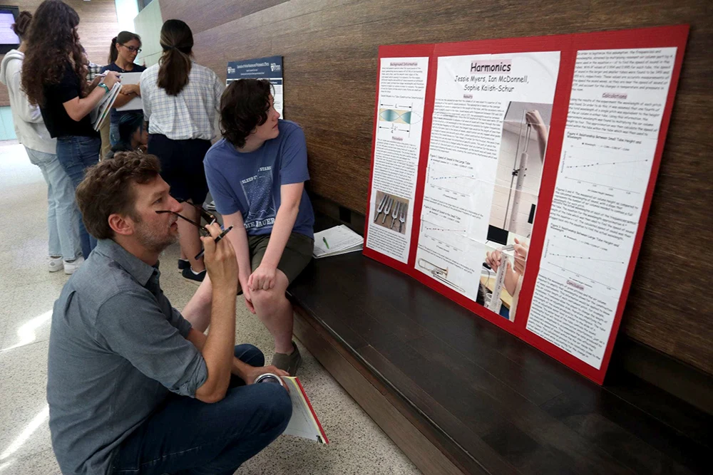 A discussion beside a student poster titled Harmonics