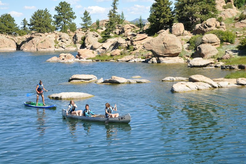 Campers canoe and paddleboard beside rocky shores