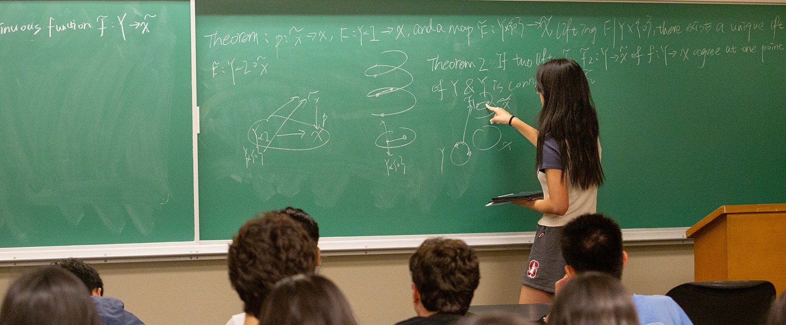 A SUMaC student explaining mathematical reasoning at the board