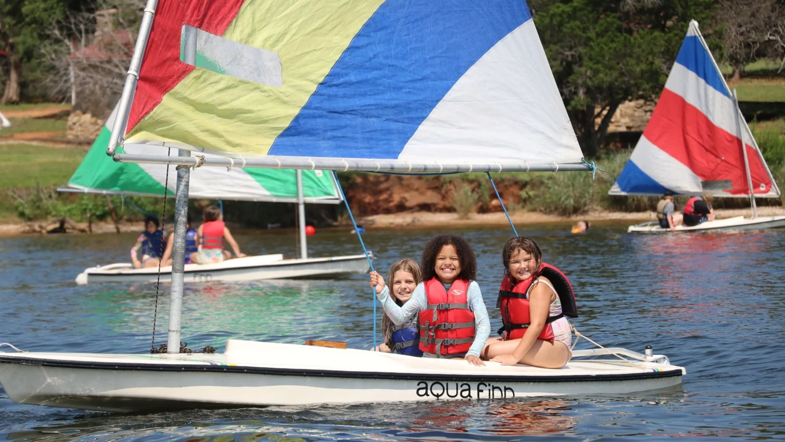 Campers sail colorful boats on the lake
