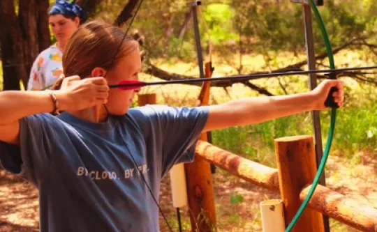 A camper takes aim at the wooded archery range
