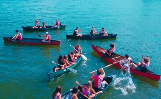 Groups of campers paddle canoes on the lake
