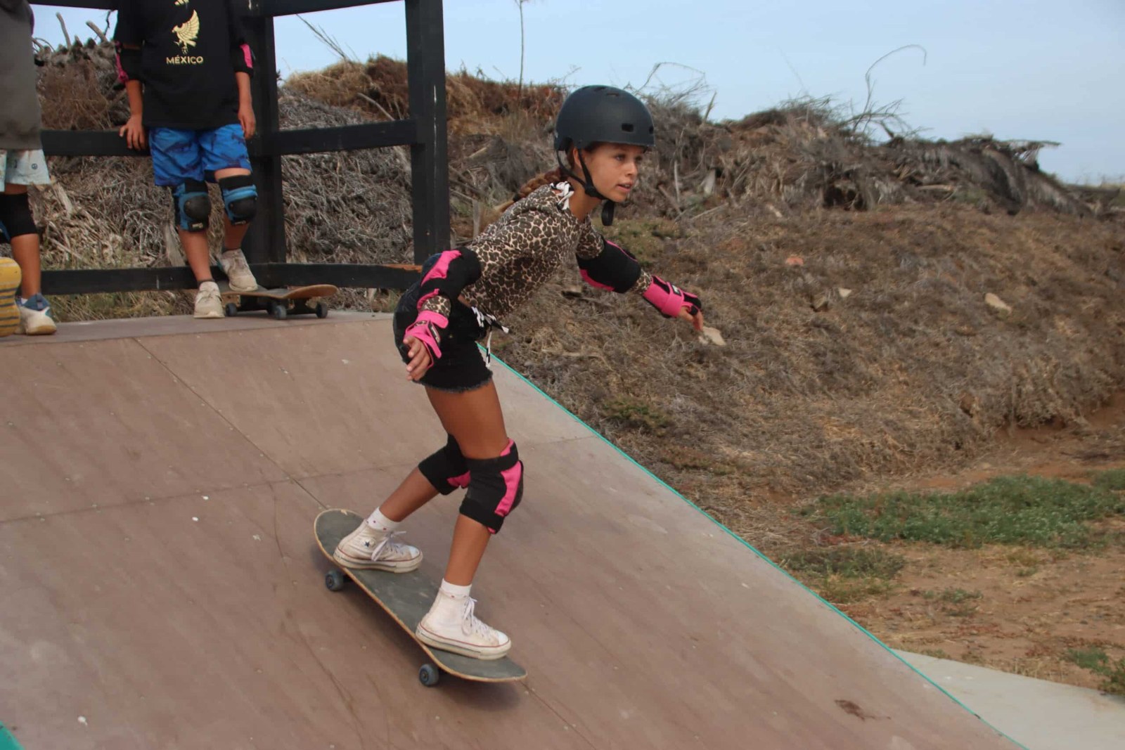A camper practises on the skate ramp with protective equipment