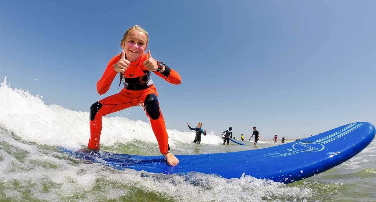 A past camper tries standing on a surfboard near shore